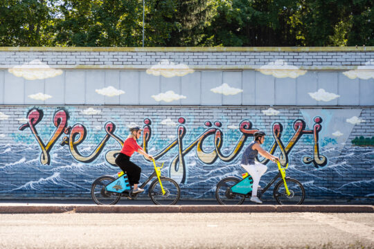 Mankeli-kMankeli-kaupunkipyörällä ajavat naiset Teivaan sataman Vesijärvi-muraalin edustalla Lahdessaaupunkipyörällä ajavat naiset Teivaan Vesijärvi-muraalin edustalla Lahdessa