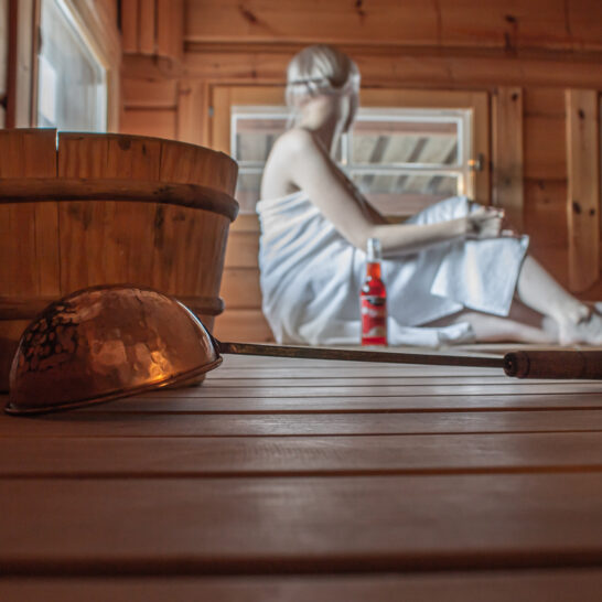 Lossirannan kartanon sauna, nainen istuu lauteilla ja katsoo ikkunasta ulos