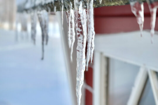 Lähikuva grillikodan räystäältä tippuvista jääpuikoista