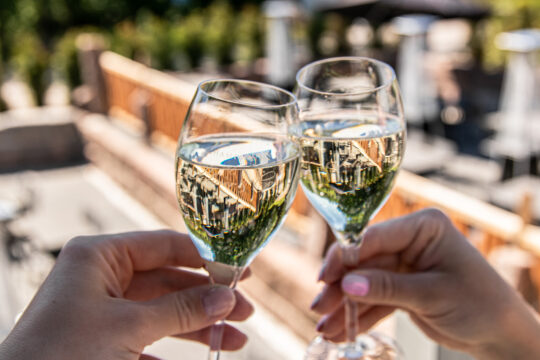 Navetan Wintti terassi ja kuohuviinilaseja kohottavat kädet kesäisenä päivänä