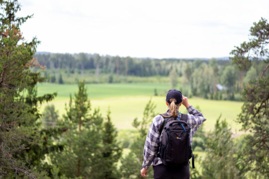Retkeilijä katselee korkealta avautuvaa peltomaisemaa