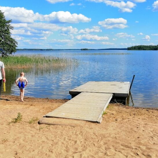 Aikuinen ja lapsi kävelevät hiekkarannalla