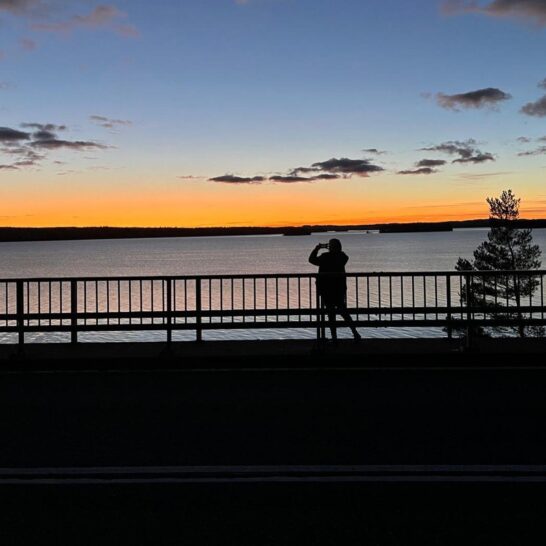 Ihminen ottaa kuvaa auringonlaskusta Karisalmen sillalla