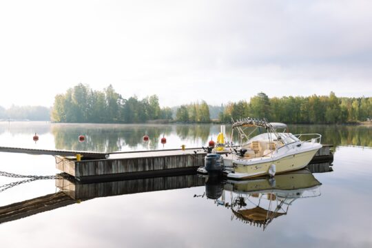 Vaalea moottorivene Ilola Innin laiturissa. Tyyni Päijänne.