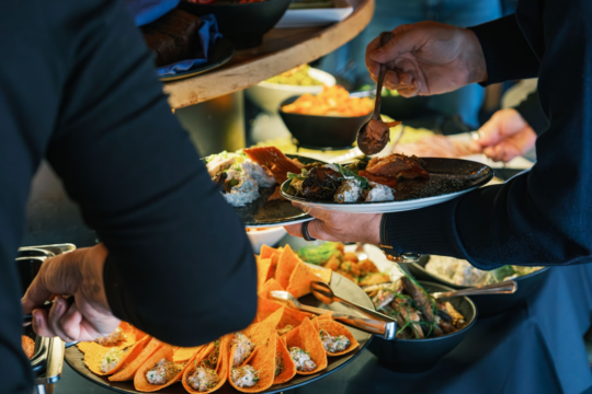 Ihmisiä ottamassa ruokaa brunssipöydästä